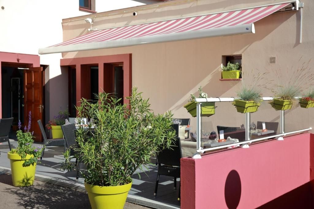 An outdoor seating area with yellow planters, a red awning, and a building with a beige facade.