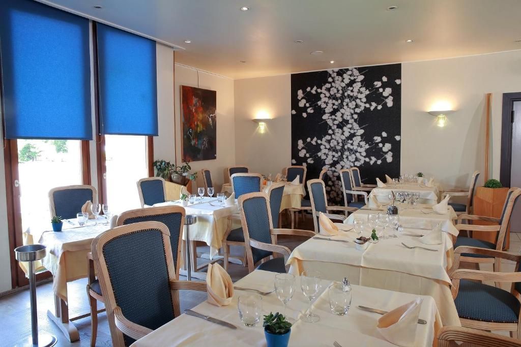 A restaurant with round tables, chairs, and a large floral wall art piece.