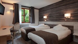 A hotel room with two beds, a desk, a chair, a TV, and a window with curtains. - Le Luth (Mirecourt)