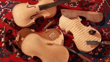 A violin, a bow, and a knife on a patterned carpet.