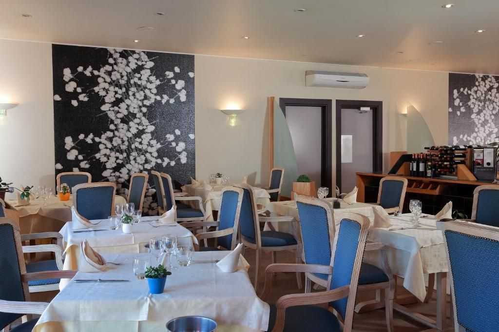 A restaurant with multiple tables, chairs, and a wall with a floral design.