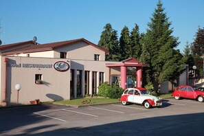 A building with a sign reading "Hotel Restaurant" and a parking lot with vintage cars. - Le Luth (Mirecourt)