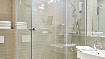 A modern bathroom with a glass-enclosed shower, a white sink, and a toilet.