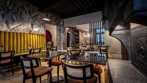 A restaurant interior with a modern design, featuring a mix of wooden and fabric textures on the walls, and a variety of seating arrangements including tables and chairs. - Hotel De Guise (Nancy)
