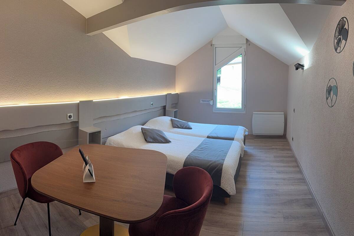 Un dormitorio con dos camas, una mesa y dos sillas.
