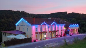 A hotel with a red roof, multiple windows, and a sign reading 'HOTEL DE LA GRANDE CASCADE.' - Hotel De la Grande Cascade (Le Tholy)