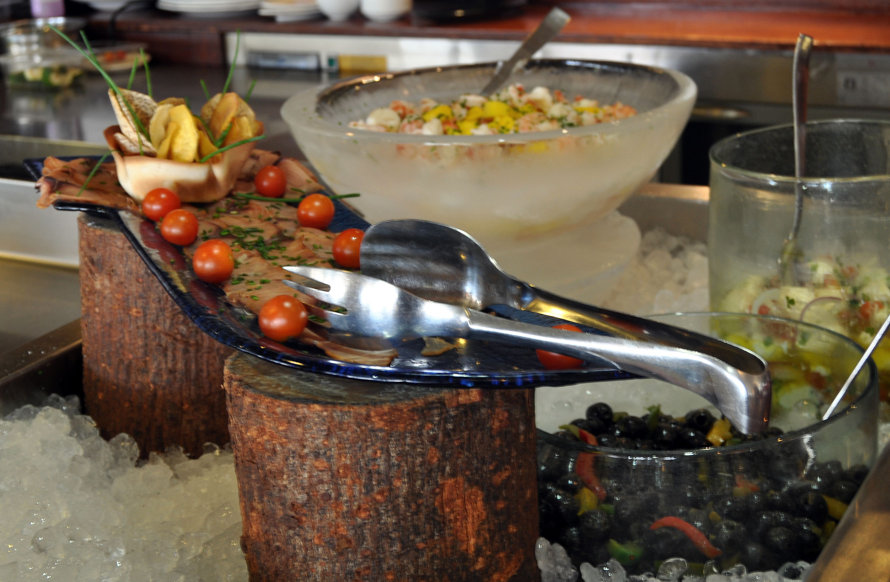 A buffet setup with various dishes and utensils on ice.