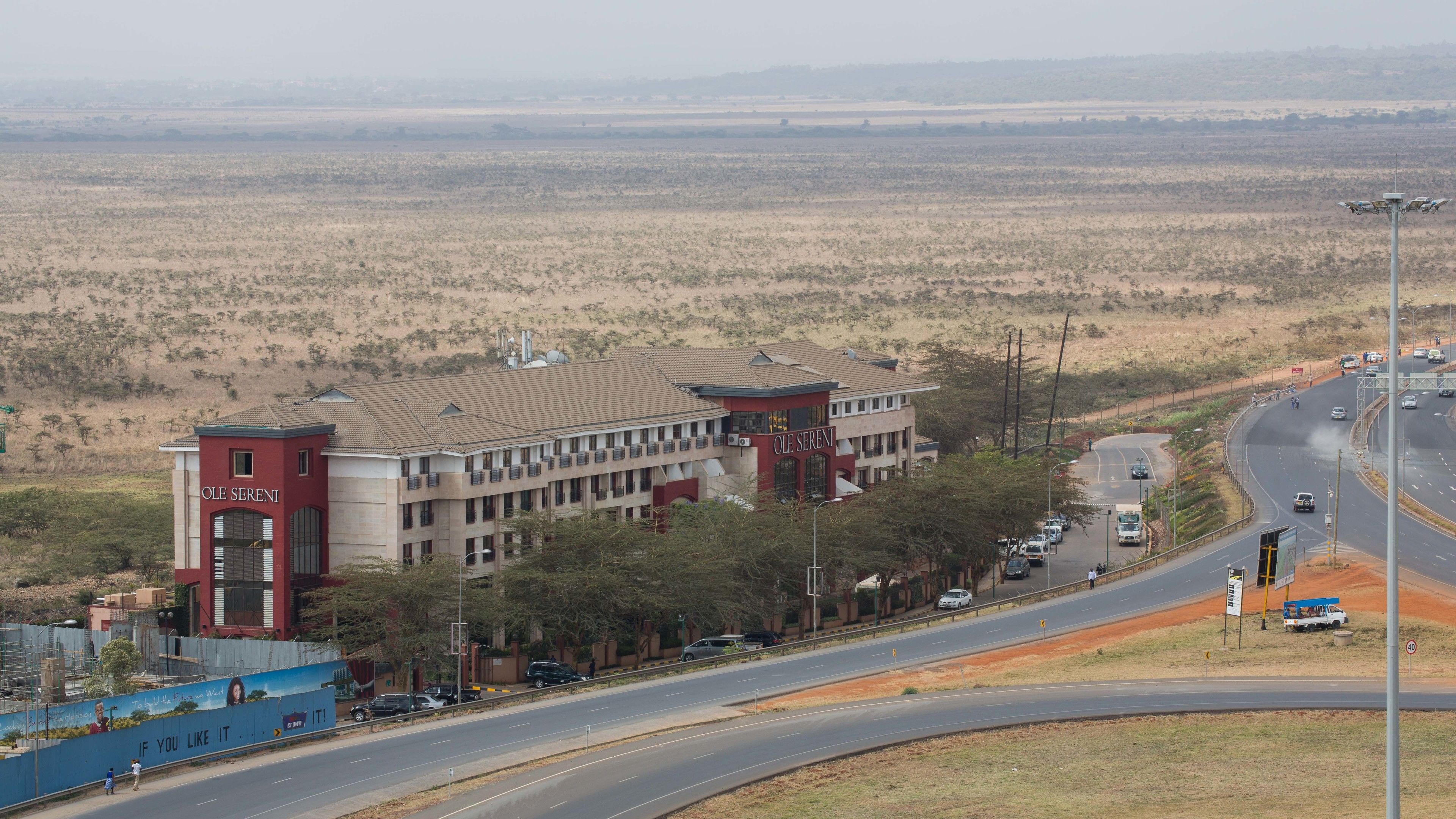 A building with a sign reading "OLE SERENI" and a road with vehicles.