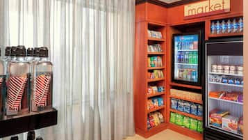 Una habitación con un refrigerador lleno de bebidas, un estante con bocadillos y una sección llamada 'the market' con diversos productos alimenticios.