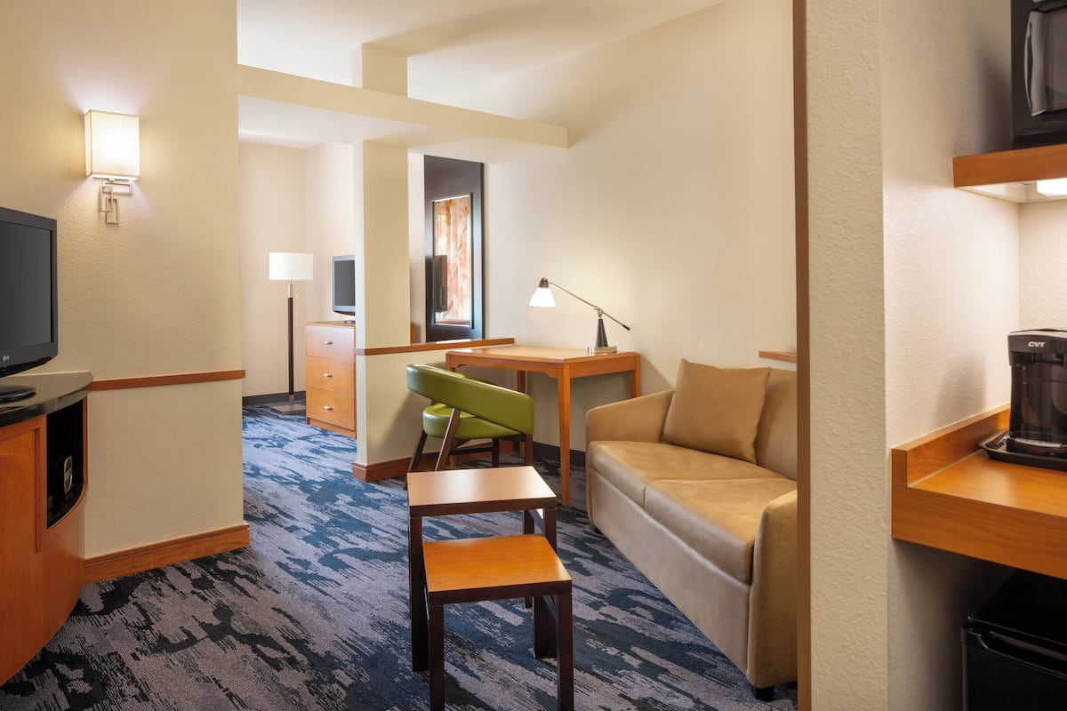 Une chambre d’hôtel équipée d’un canapé, d’un bureau avec une lampe, d’une télévision et d’une machine à café.