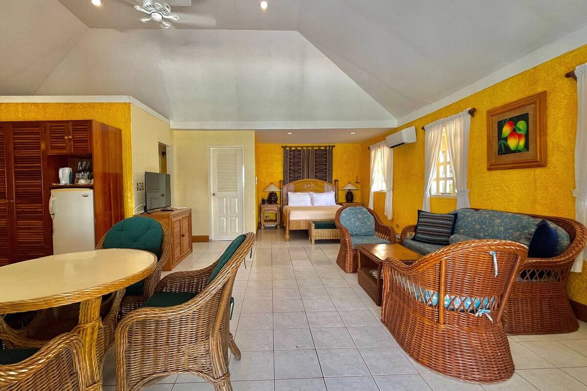 A spacious living area with wicker furniture, a dining table, and a TV.