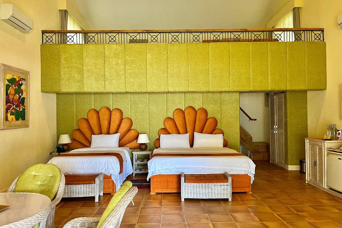 A hotel room with two beds, a balcony, wicker furniture, and a tiled floor.