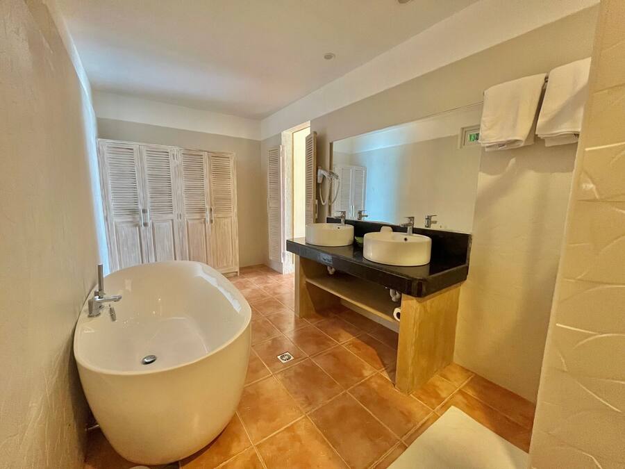 A bathroom with a large bathtub, two sinks, a mirror, and a towel rack.