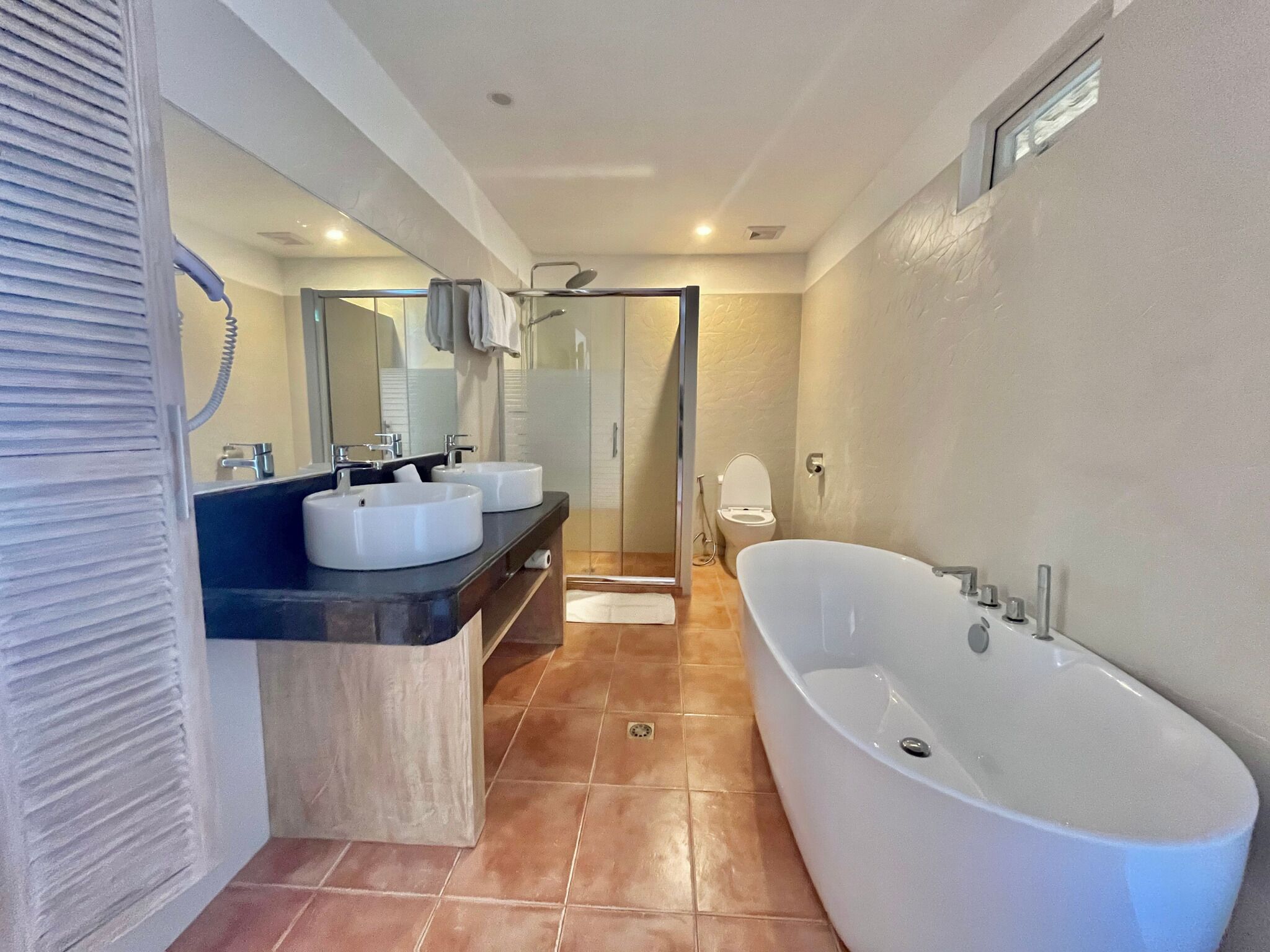 Ein modernes Badezimmer mit einer großen Badewanne, zwei Waschbecken und einer Duschkabine aus Glas.