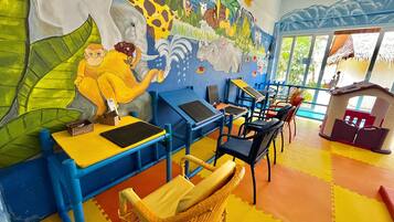 Zona de juegos infantiles con mobiliario colorido y un mural de animales.