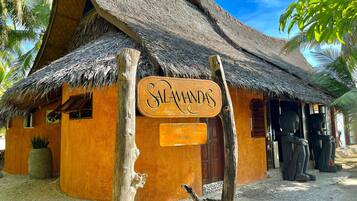 A rustic building with a thatched roof and a sign reading "SALAMANDAS".