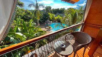 Relax on the balcony overlooking the serene pool surrounded by lush vegetation.