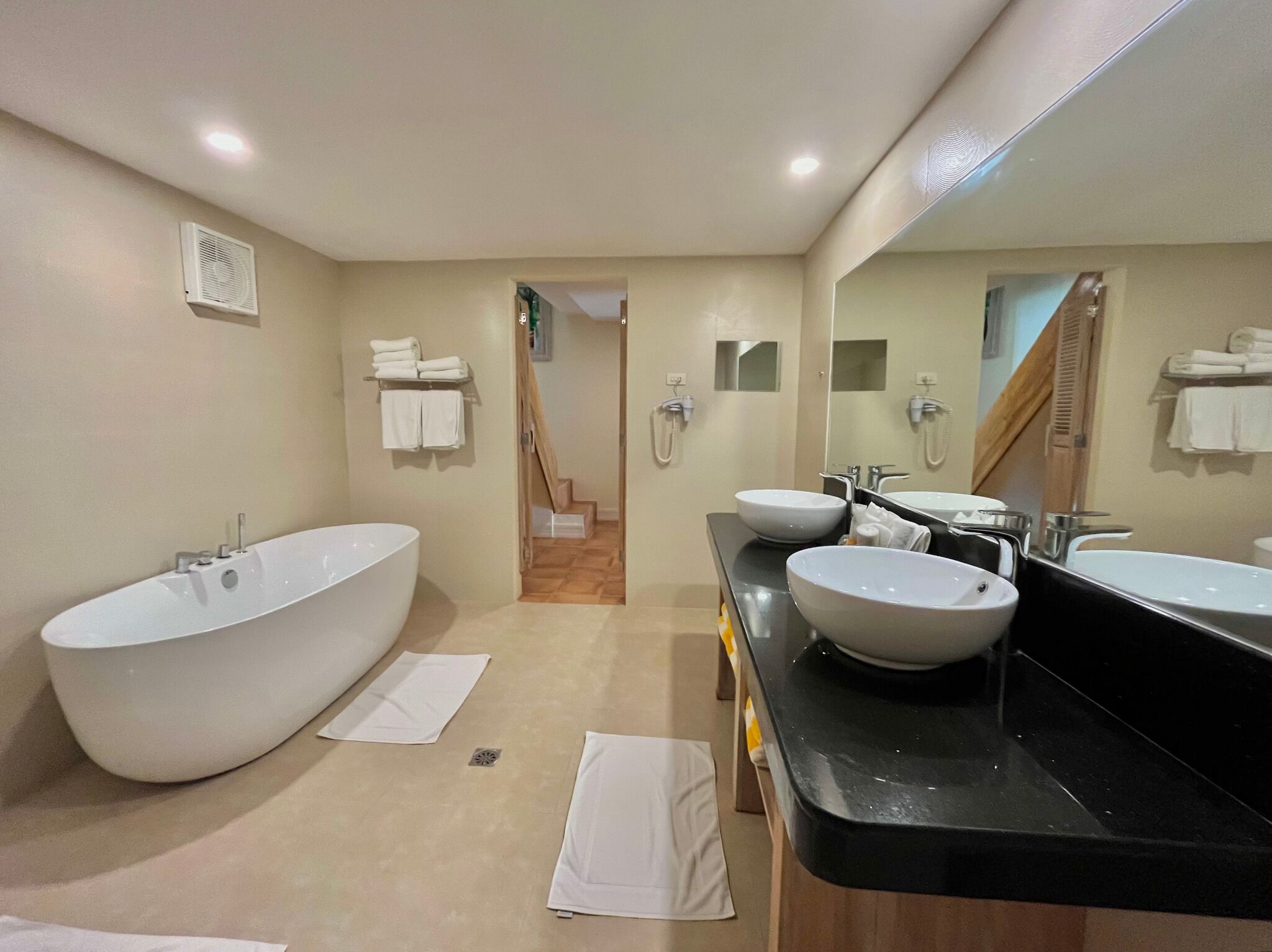A modern bathroom with a freestanding bathtub, two sinks, and a large mirror.