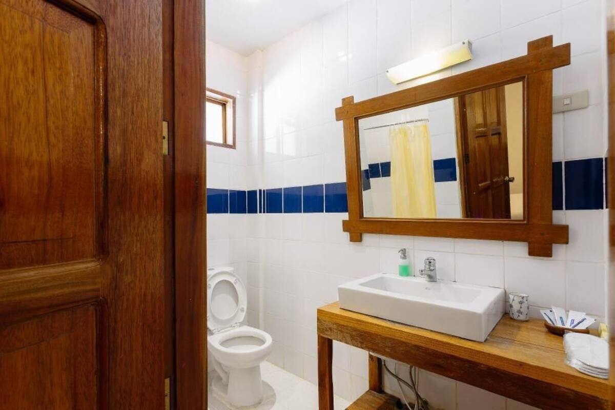 A bathroom with a wooden door, white toilet, and a sink with a mirror above it.