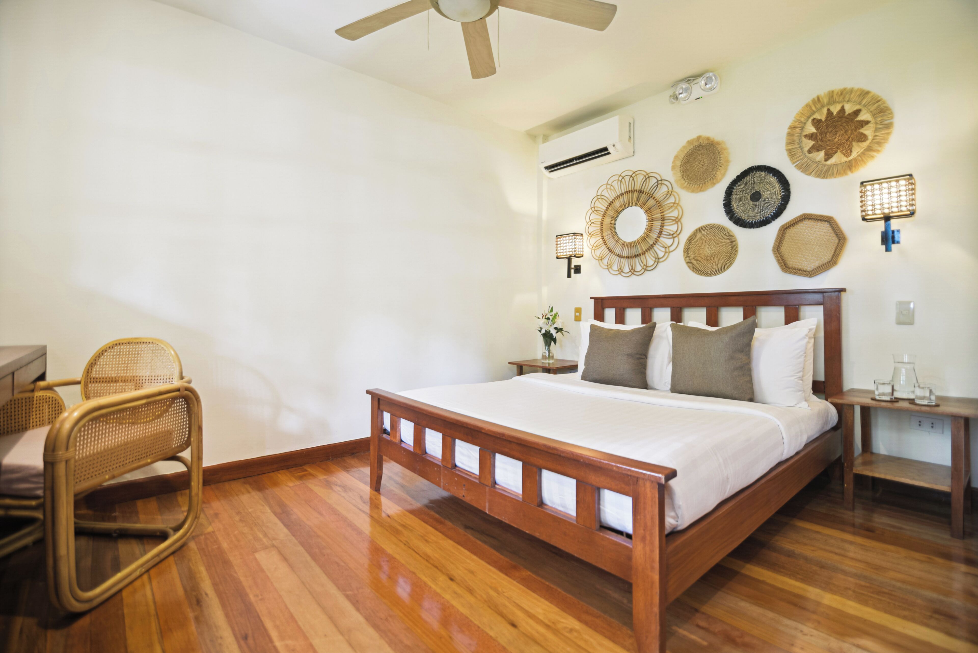 A bedroom with a wooden bed, a wicker chair, and wall decor.