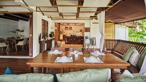 Un comedor amplio con una mesa de madera dispuesta para cuatro personas, rodeado de asientos tapizados en verde.