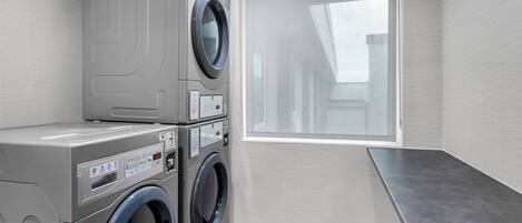 A laundry room with a washing machine and dryer, a control panel, and a window with a view.