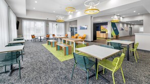 Eine moderne Hotelhalle mit mehreren Sitzbereichen, einer Rezeption und einem großen Fenster mit Vorhängen.