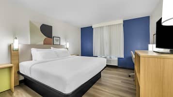 A modern hotel room with a large bed, bedside tables, a desk, and a window with curtains.