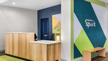 A reception desk with a wooden finish, a blue door, and a wall with geometric patterns and the text 'Lionely takes a spark'.