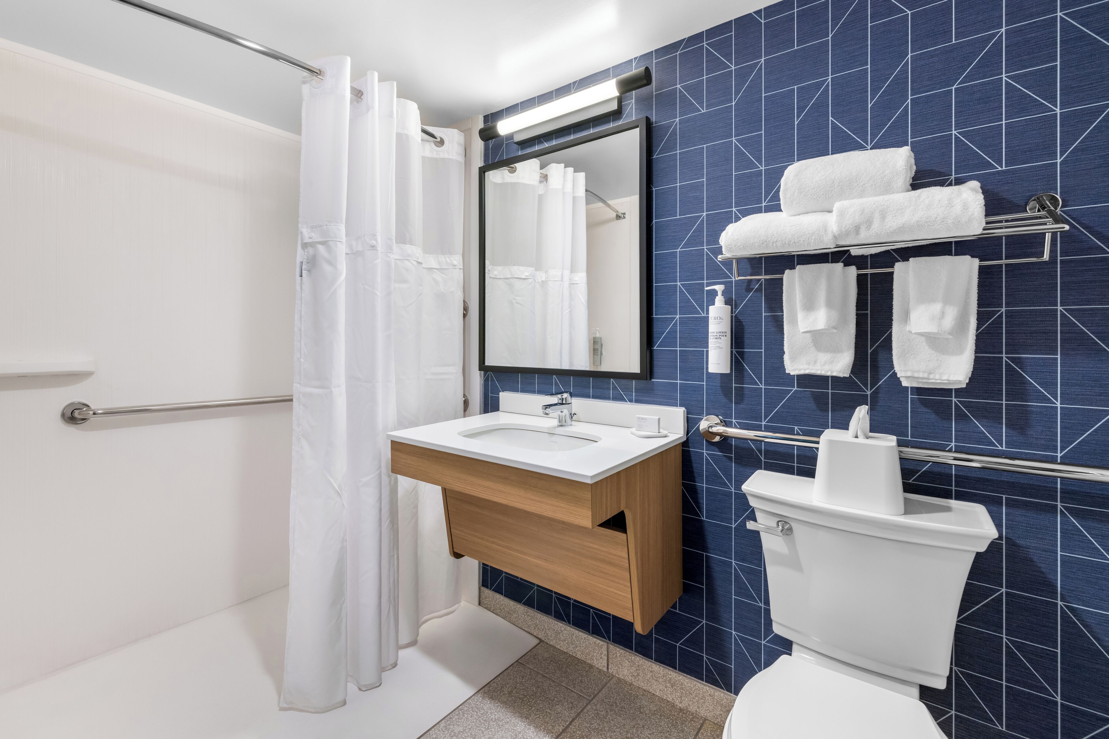 Un baño moderno con ducha, lavamanos, inodoro y un perchero para toallas.