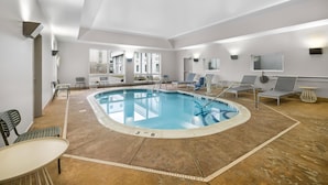 Ein Swimmingpool mit Wassertiefenmarkierung zwischen 90 Zentimetern und 1,80 Metern, Liegestühlen und Tischen rund um das Pool-Areal.