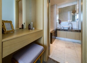 A modern bathroom with a wooden vanity, a bench, a sink with a marble countertop, and a large mirror. - Harbor Park Hotel (Incheon)