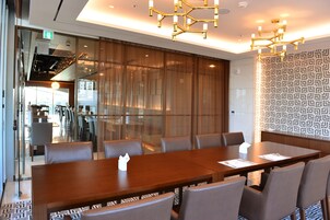 A conference room with a long table, multiple chairs, and a patterned wall.