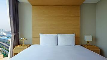 A hotel room with a large bed, two bedside tables, a lamp, and a view of a cityscape.