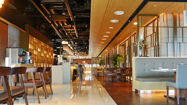 A modern restaurant with wooden chairs, a bar area, and a seating section with a cushioned bench. - Harbor Park Hotel (Incheon)