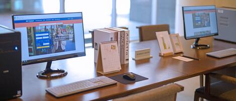 A workspace with two desktop computers, a keyboard, a mouse, and a calendar on a wooden table.