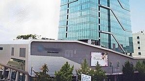 A modern glass building with a unique angular design, a visible sign for Monkey Park Hotel, and a clear blue sky with clouds. - Harbor Park Hotel (Incheon)