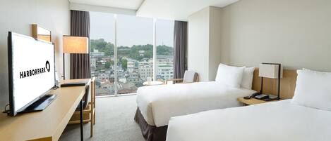 Habitación de hotel con dos camas, un escritorio, una televisión y vistas a la ciudad.