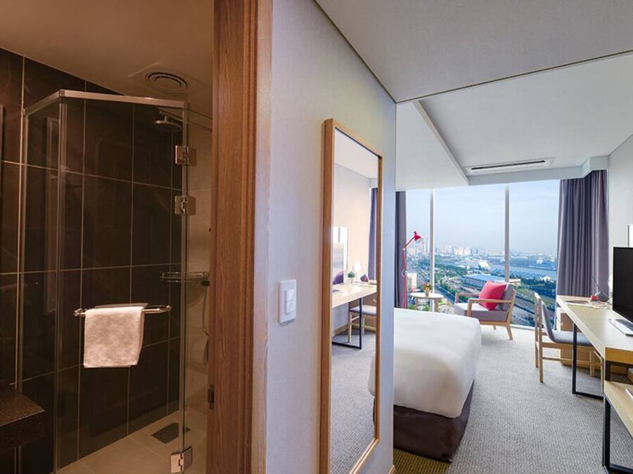 Habitación de hotel con baño, cama, escritorio y vistas a la ciudad.