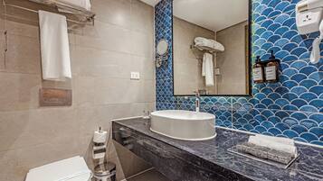 A modern bathroom with a white sink, a mirror, and a blue tiled wall.