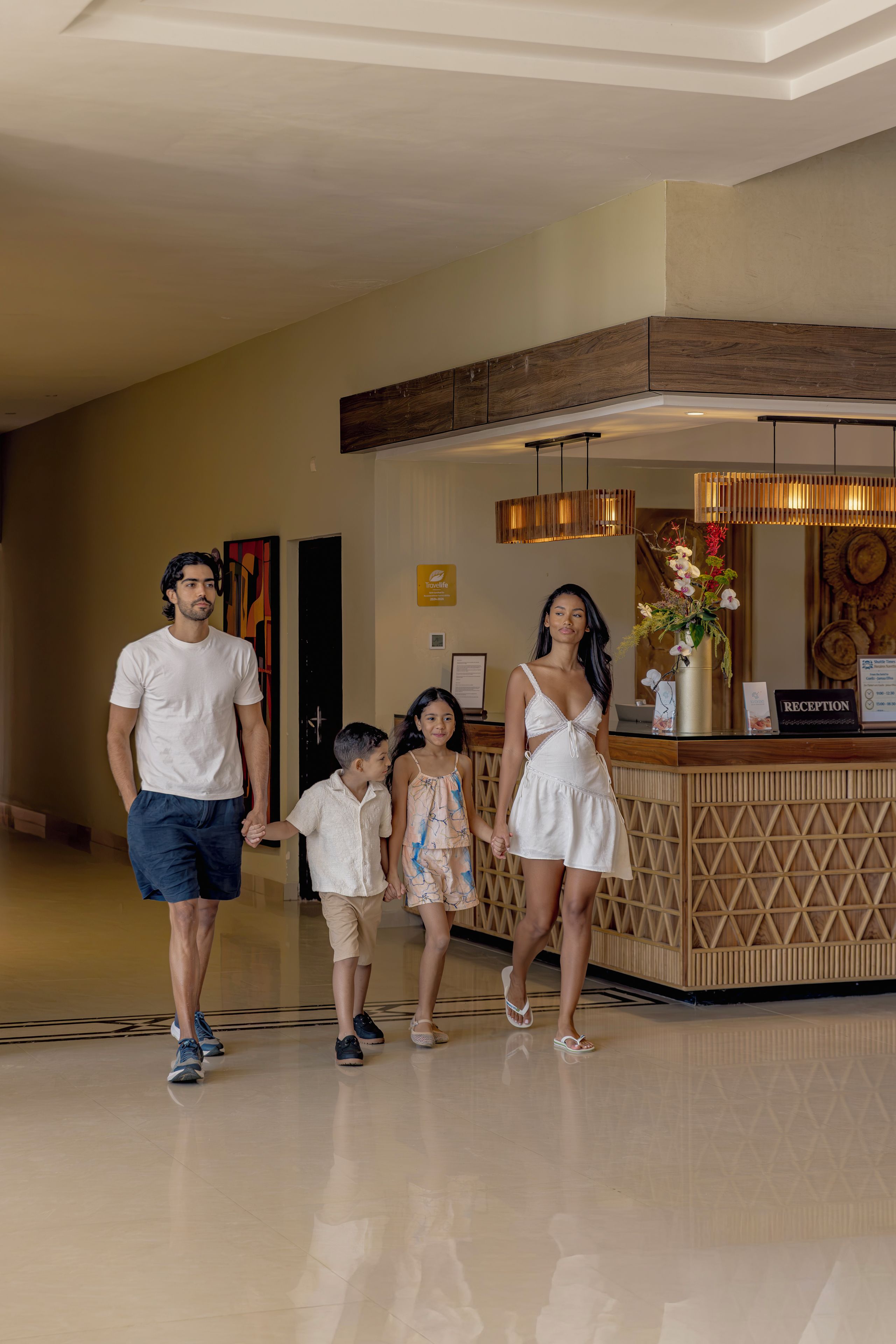 A family walking through a hotel lobby with a reception desk and a wooden reception area.