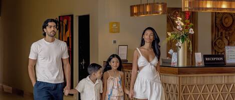 A family walking through a hotel lobby with a reception desk and a wooden reception area.