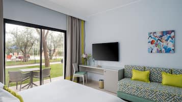 Habitación de hotel con cama, escritorio, sofá, televisor y vistas al exterior.