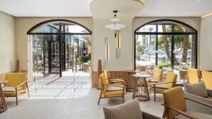 A modern lobby with a pool view, featuring wooden furniture, glass doors, and a central light fixture. - Aqualis Club Resort Marrakech (Marrakech)