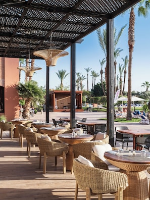 An outdoor seating area with wicker furniture and a view of palm trees. - Labranda Targa Club Aqua Parc (Marrakech)