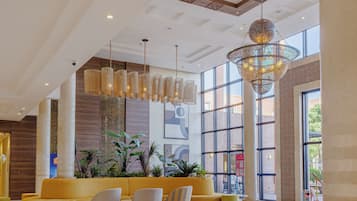 Eine geräumige Lobby mit modernen Möbeln, großen Fenstern und dekorativer Beleuchtung.