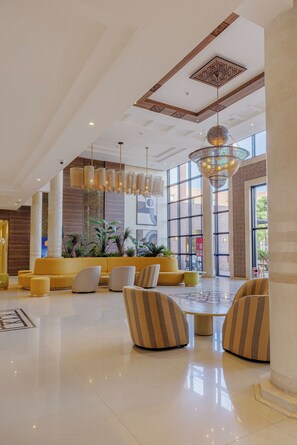 Un vestíbulo amplio con muebles modernos, ventanas grandes y lámparas decorativas.
