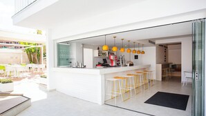 A modern kitchen with a bar area, white cabinetry, and yellow pendant lights. - BQ Carmen Playa Hotel - Adults Only (Palma de Mallorca)