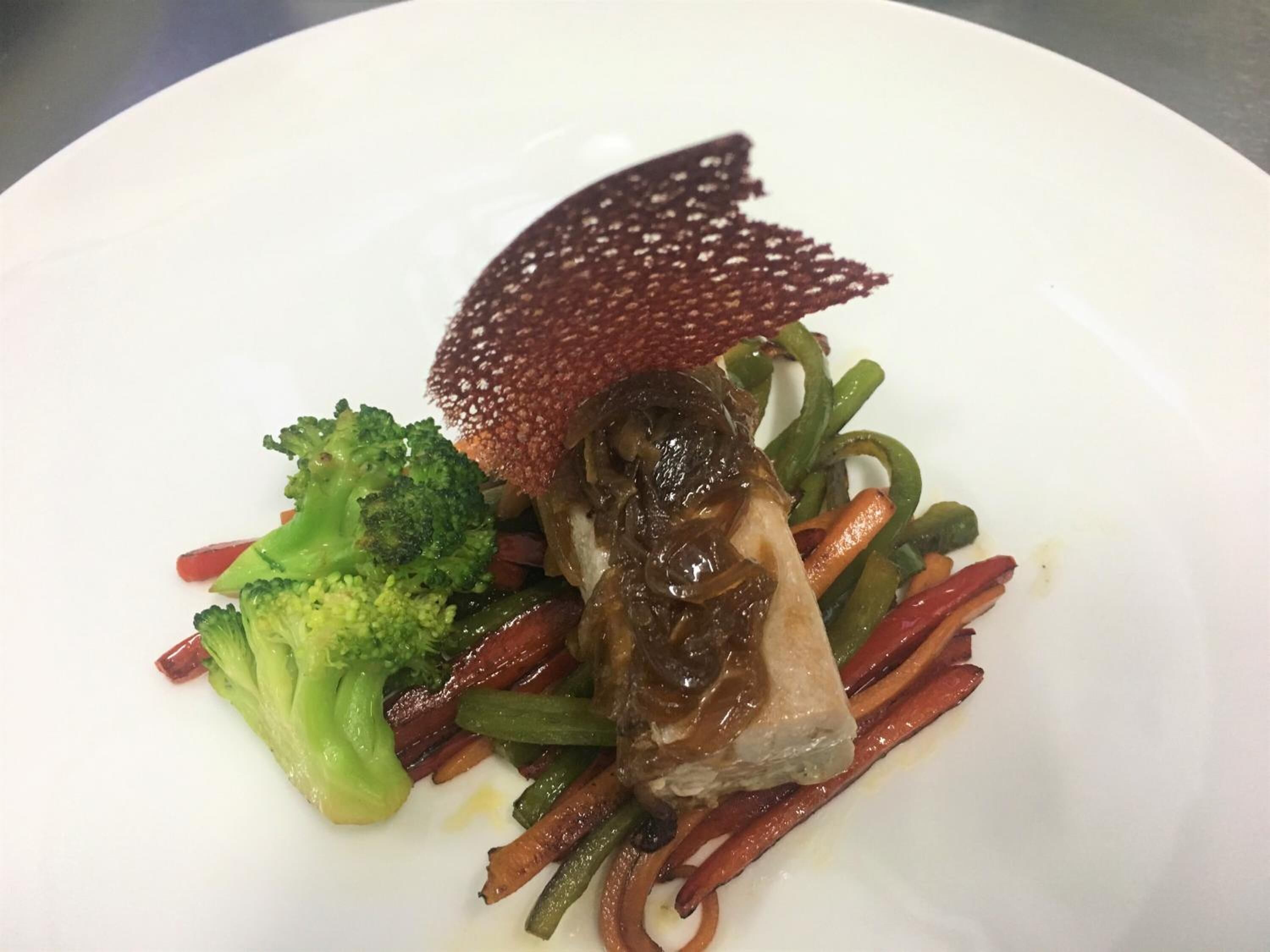 Ein Teller mit Fleisch, Brokkoli und geschnittenem Gemüse.