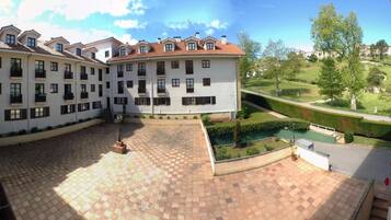 Ein Innenhof mit gefliestem Boden, einem Pool und einem Gebäude mit mehreren Balkonen.